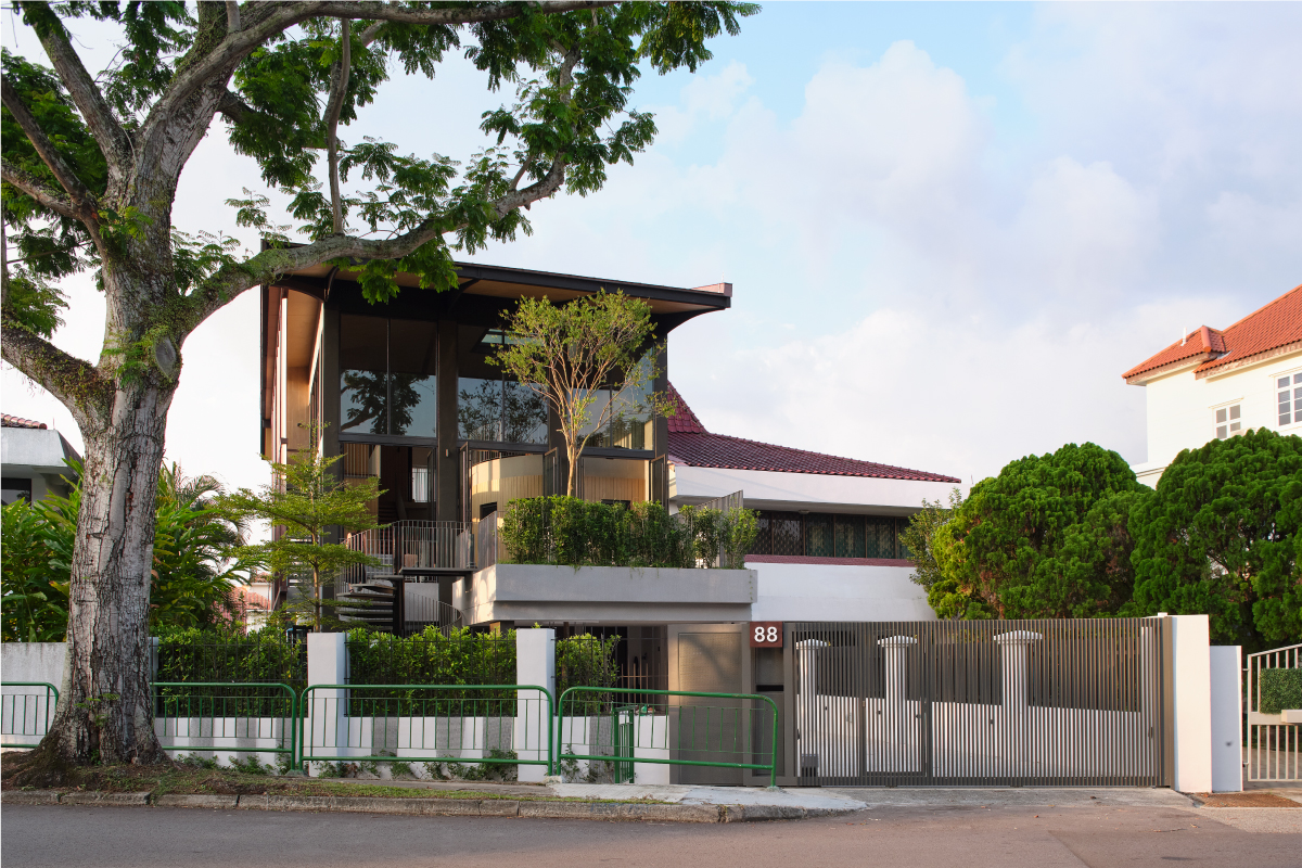 The upper storeys of the house seen through surrounding trees, with greenery spilling from the roof edge